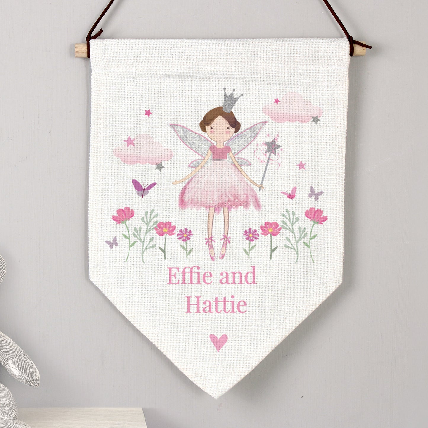 Fairy-themed decorative banner with flowers and butterflies on a white background, hanging against a gray wall.