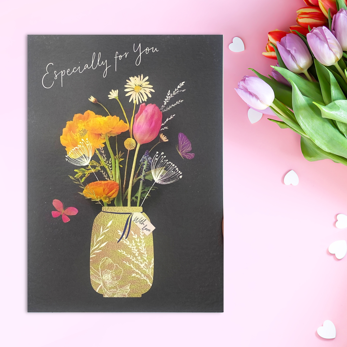 Black chalkboard background with mason jar of spring flowers laid flat