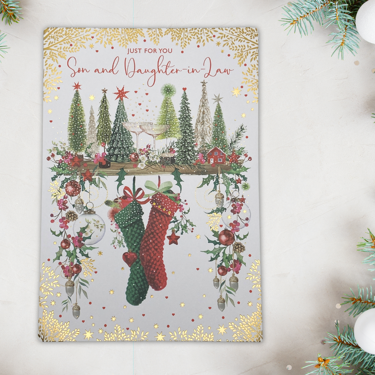 A full-coloured son-and daughter-in-law-Christmas card with gold foil details, featuring an illustration of trees, and festive decorations.