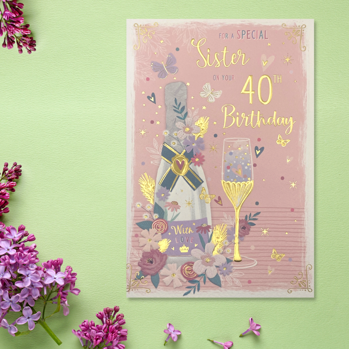 Pink card with bubbly, glass and flowers surrounded with hearts and butterflies