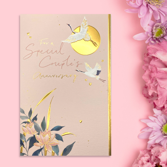 Front image of peach coloured card, flowers and stork flying past gold foil sun