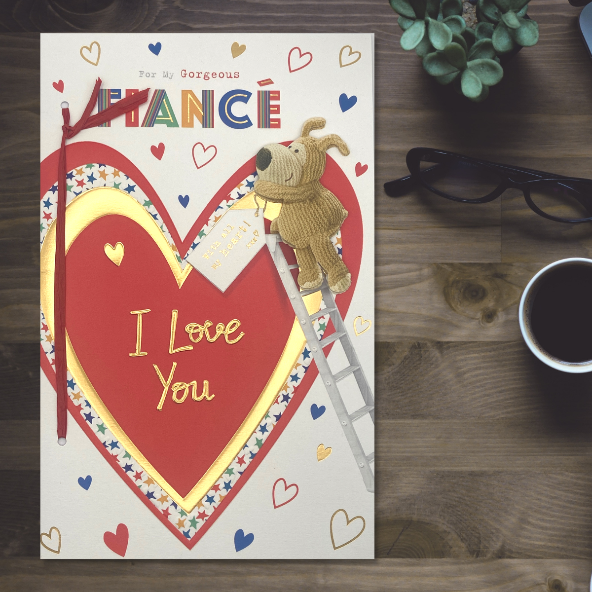 Brightly coloured text surround red and gold heart with boofle up a ladder decorating with tag