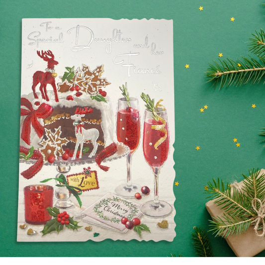 Christmas cake with two deer decorations and glasses of fizz on table