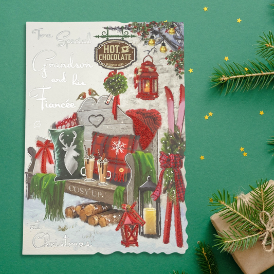 Two hot chocolates on a bench with festive items in the snow