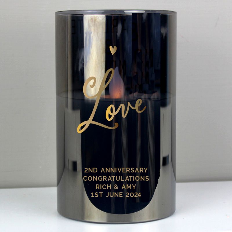 Candle holder with 'Love' and wedding anniversary details on a reflective surface