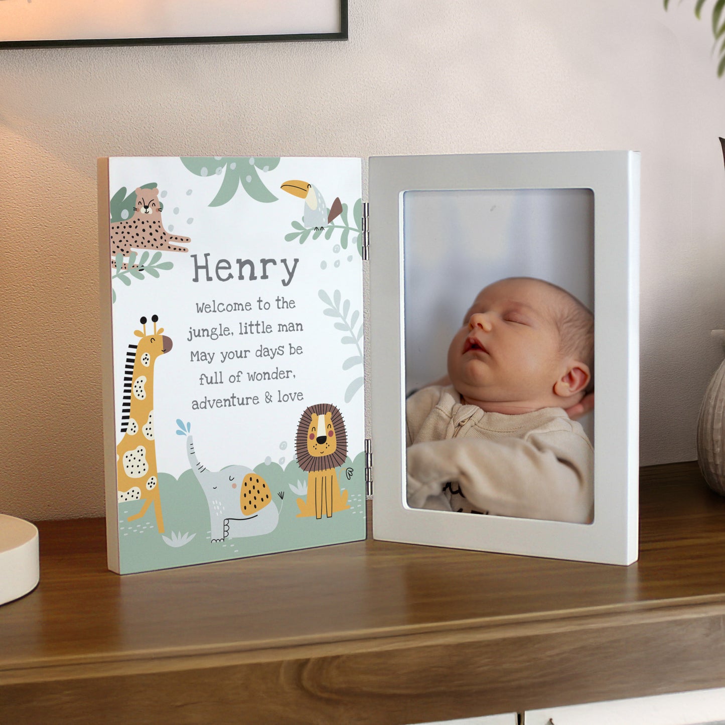 Personalised photo frame with baby's name and a cartoon animal design on a wooden surface.