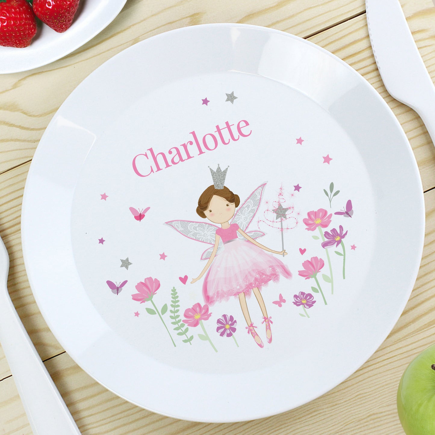 Children's plate with fairy design and name 'Charlotte' on a wooden table.
