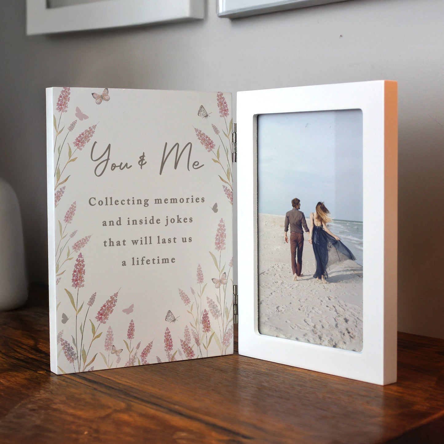 Open photo album with floral design and text, showing a couple on a beach.