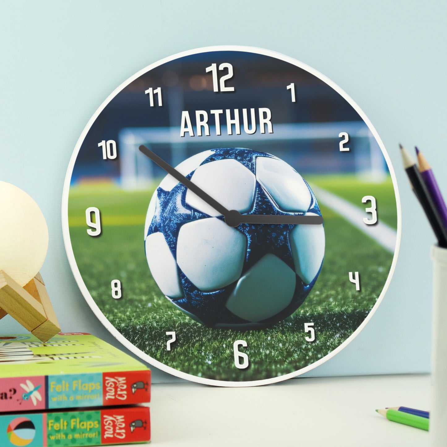 Wall clock with soccer ball design and 'Arthur' branding on a light blue background.