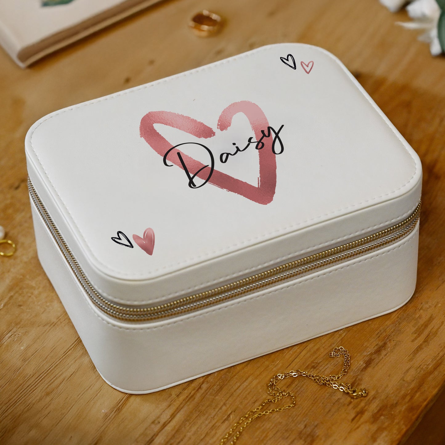 White jewelry box with 'Daisy' and heart designs on a wooden surface
