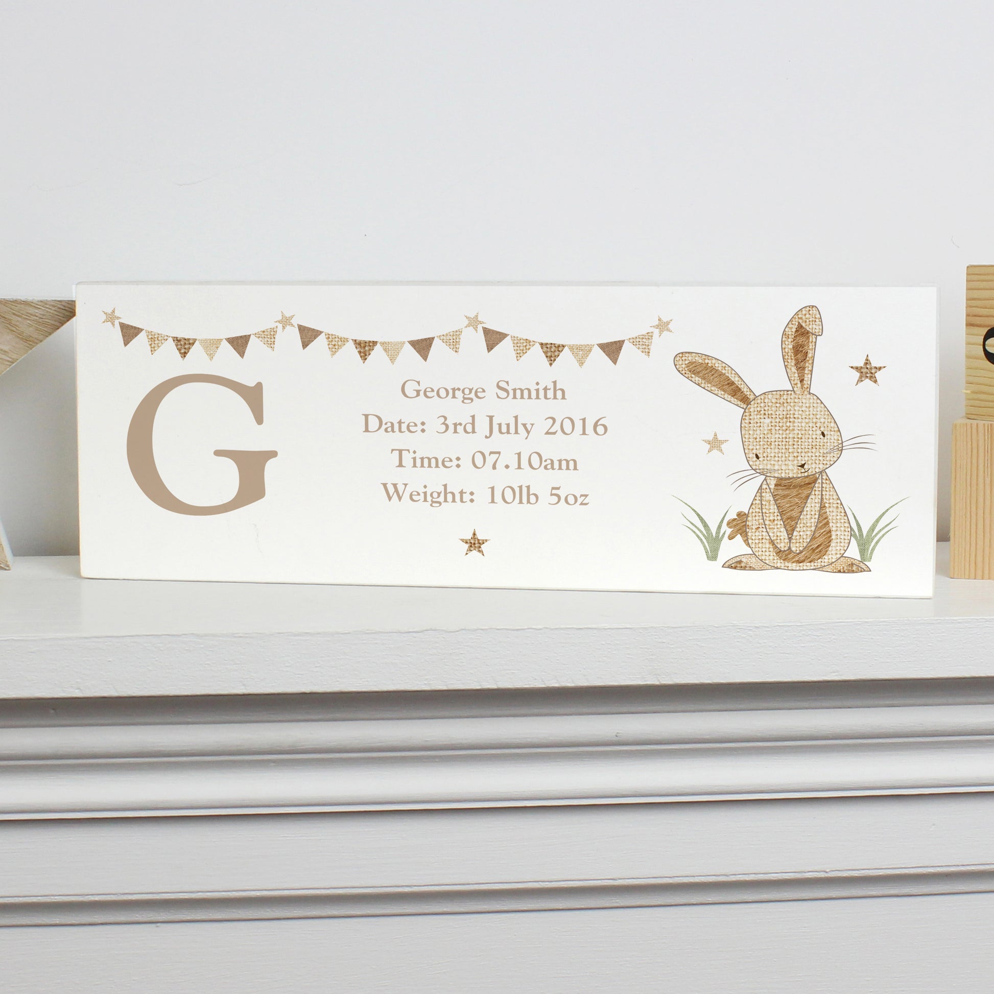 Personalised birth announcement block shown on a white shelf.