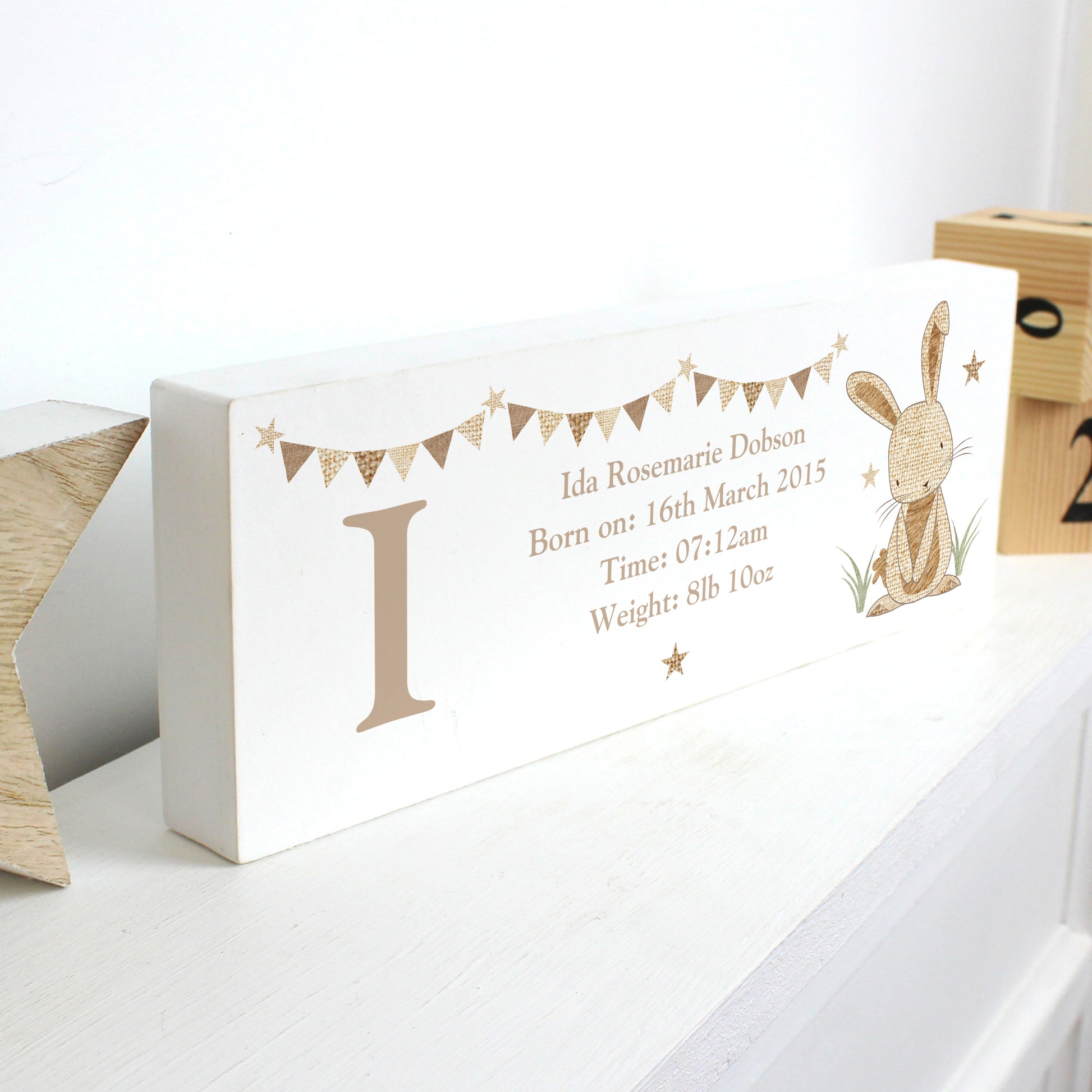 Personalised decorative block sitting on a shelf showing birth details , large initial and cute rabbit image.
