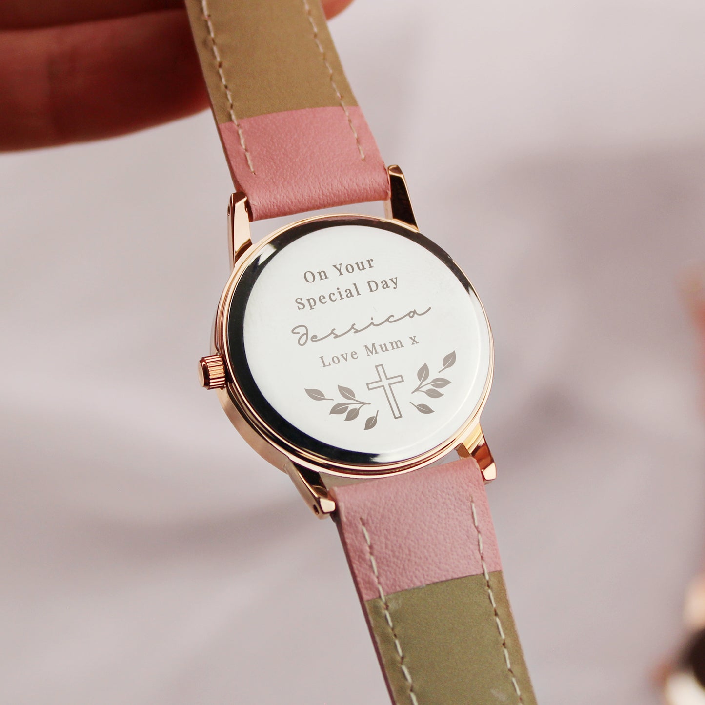 Watch with a personalised message on the dial, featuring a pink and green strap.