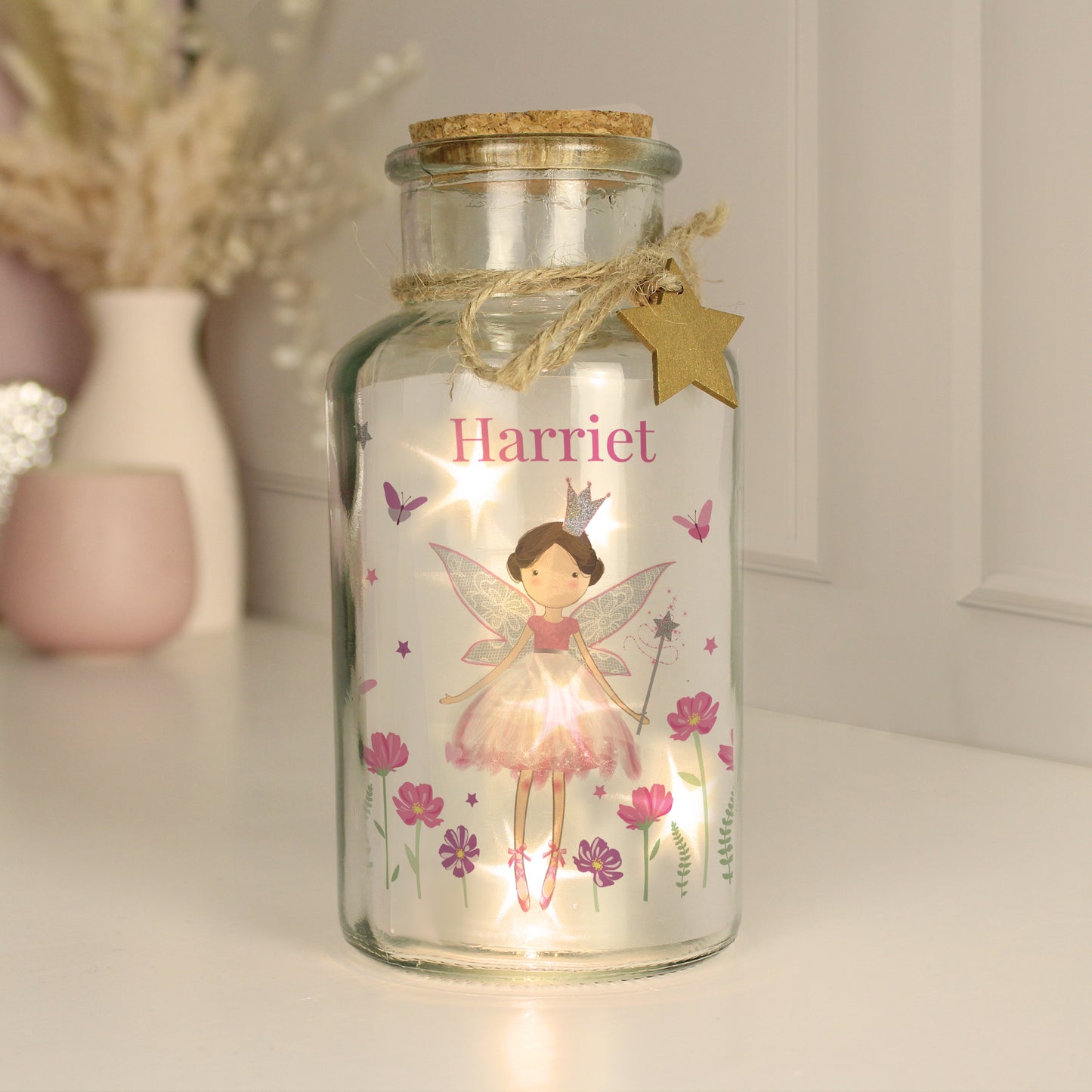 Decorative glass jar with fairy design and 'Harriet' text, featuring a light inside.