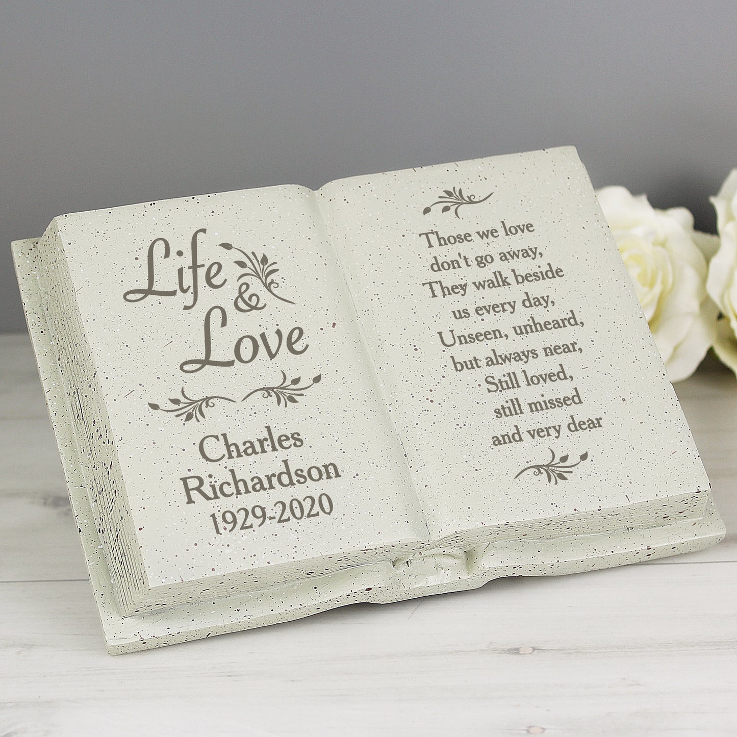 Memorial stone with engraved text and floral designs on a gray background