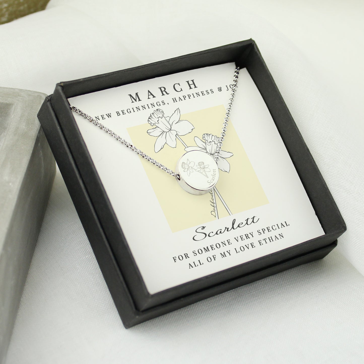 Silver necklace in a black box with a card detailing the month of birth and a message.
