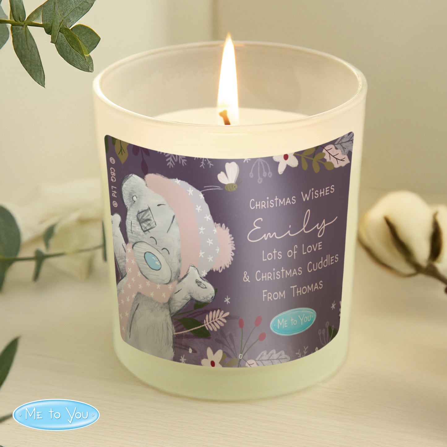 Candle with a label featuring a bear design and text on a neutral background