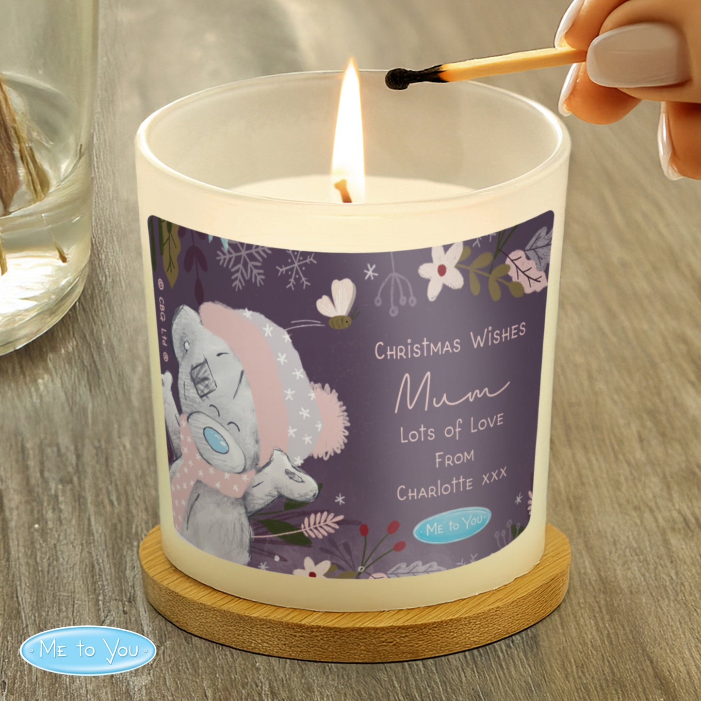 Candle being lit with a decorative label featuring a cartoon character on a wooden surface.