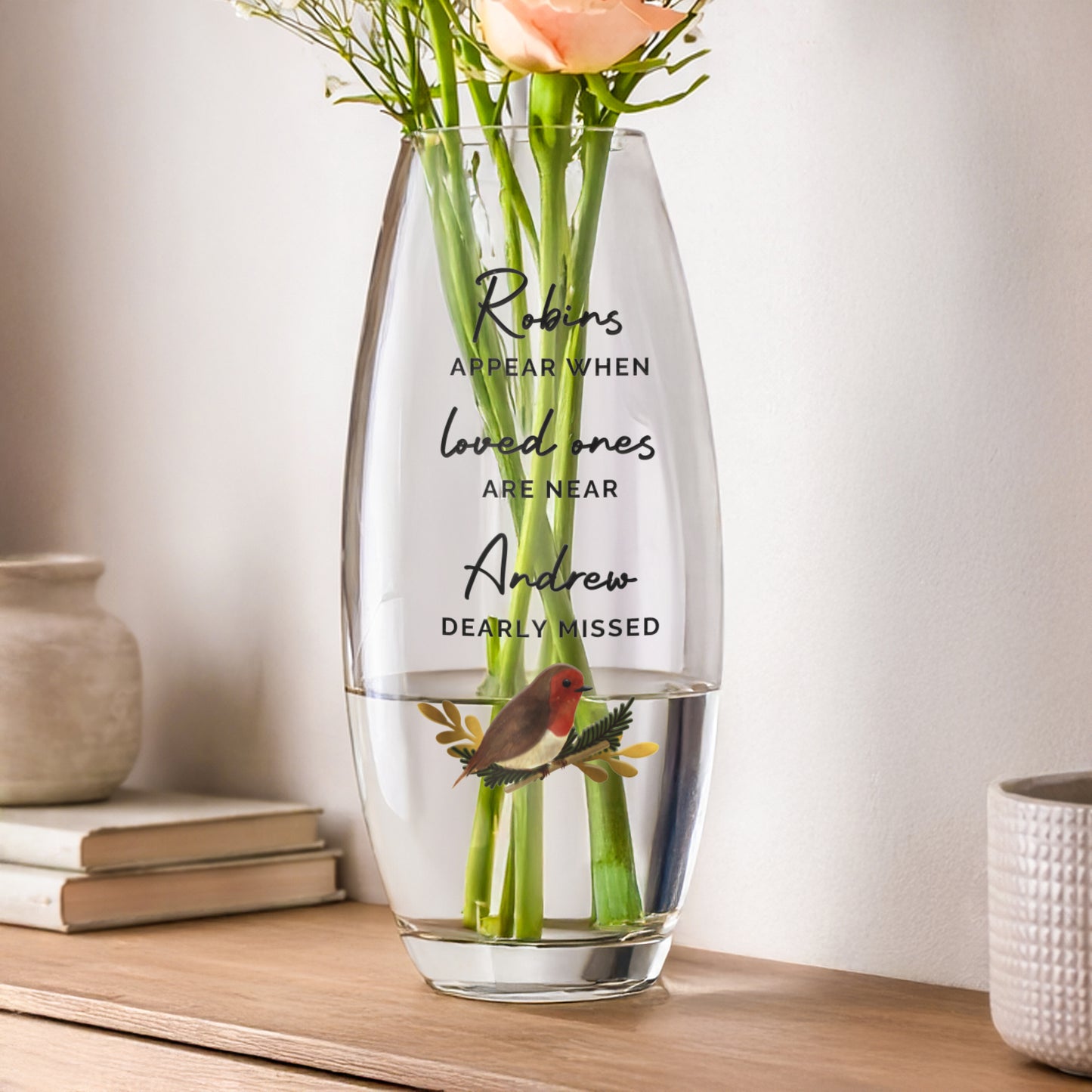 Clear glass vase with engraved text and flowers on a wooden surface