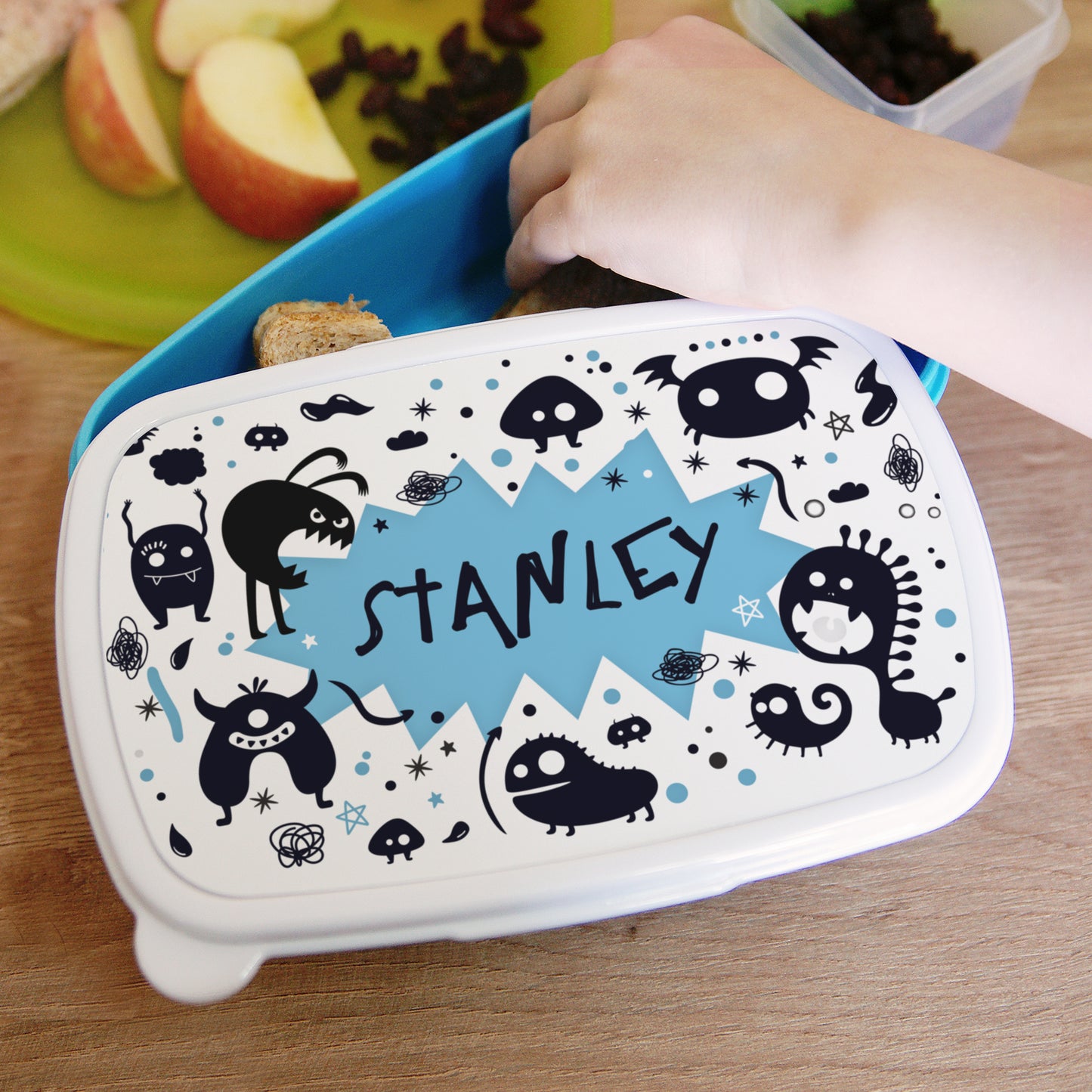 Lunch box with cartoon designs and 'Stanley' text on a wooden table.