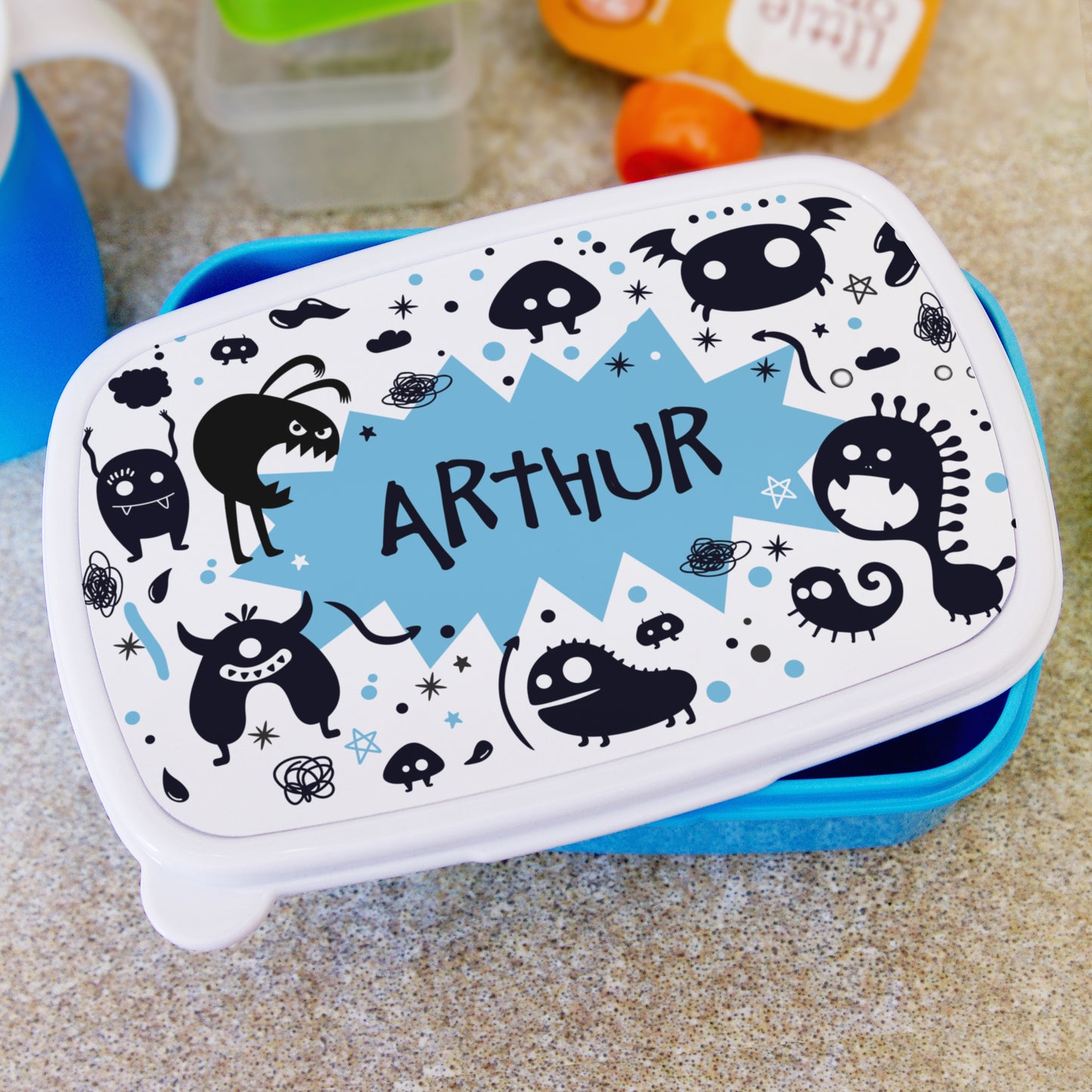 Children's lunch box with black monster design and 'ARTHUR' text on a white background.