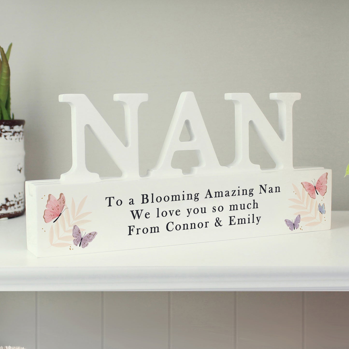 Decorative sign with 'NAN' and a message on a shelf.