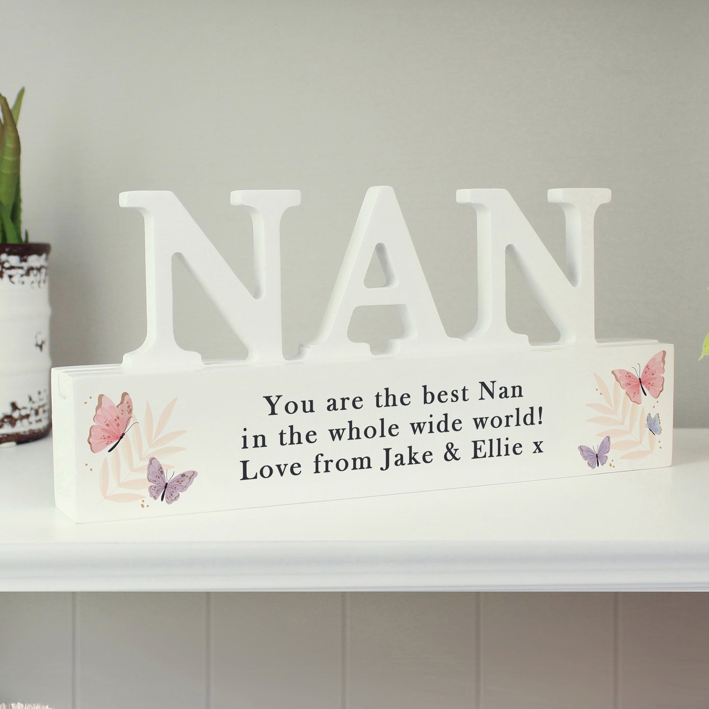 Decorative sign with 'NAN' and a message on a shelf.
