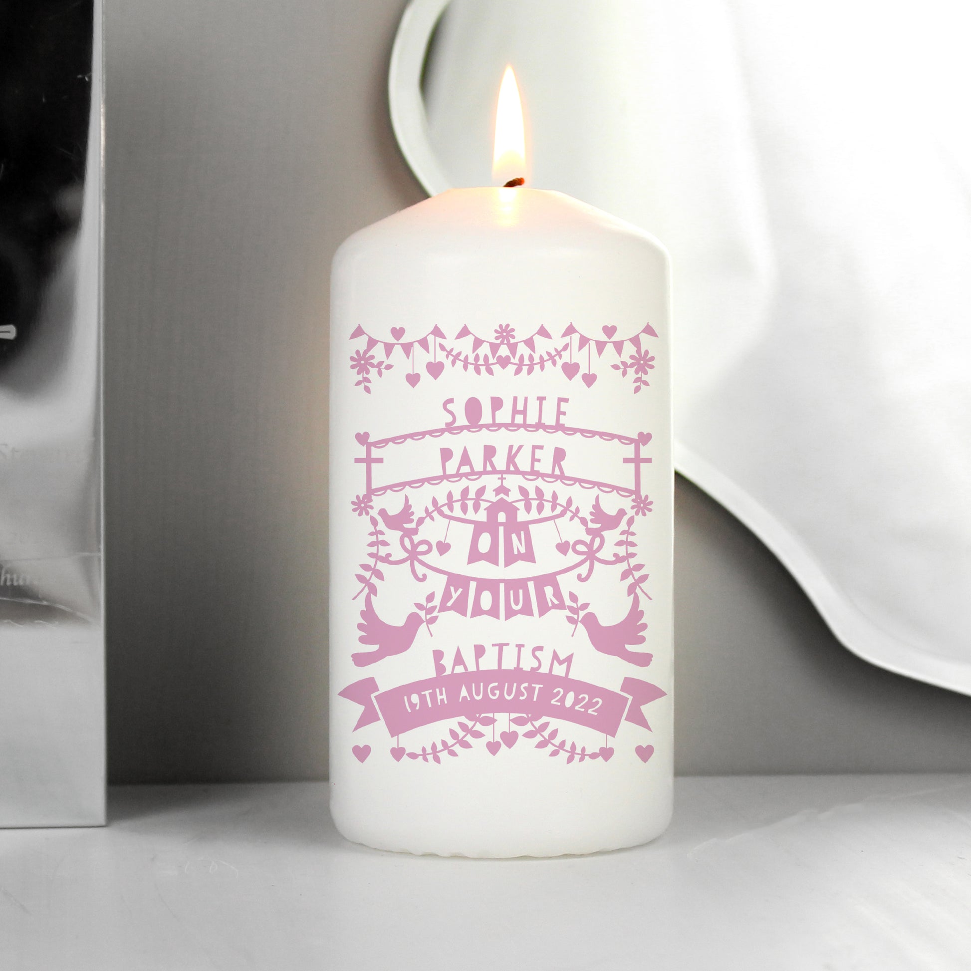 White candle with pink personalised design on a neutral background