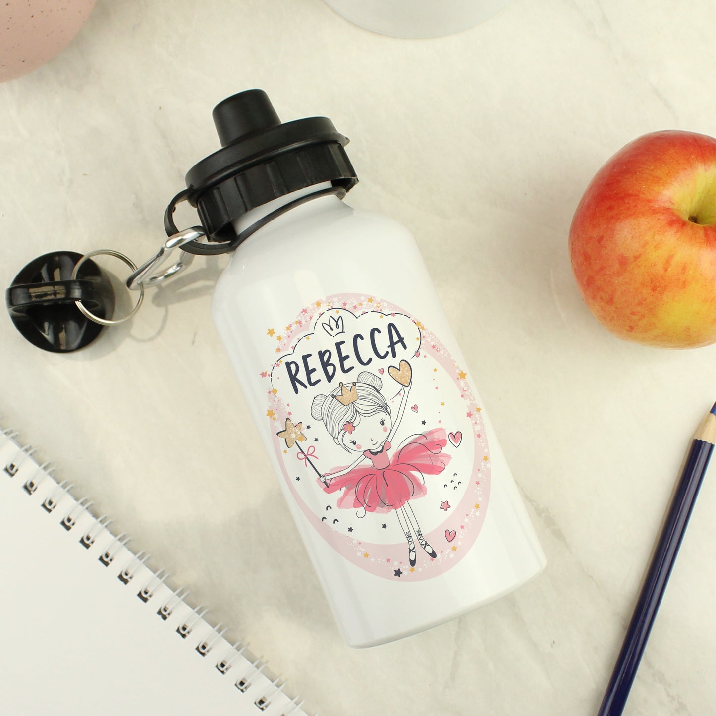 Personalized water bottle with a cartoon character and 'REBECCA' on a white surface with an apple and notebook.