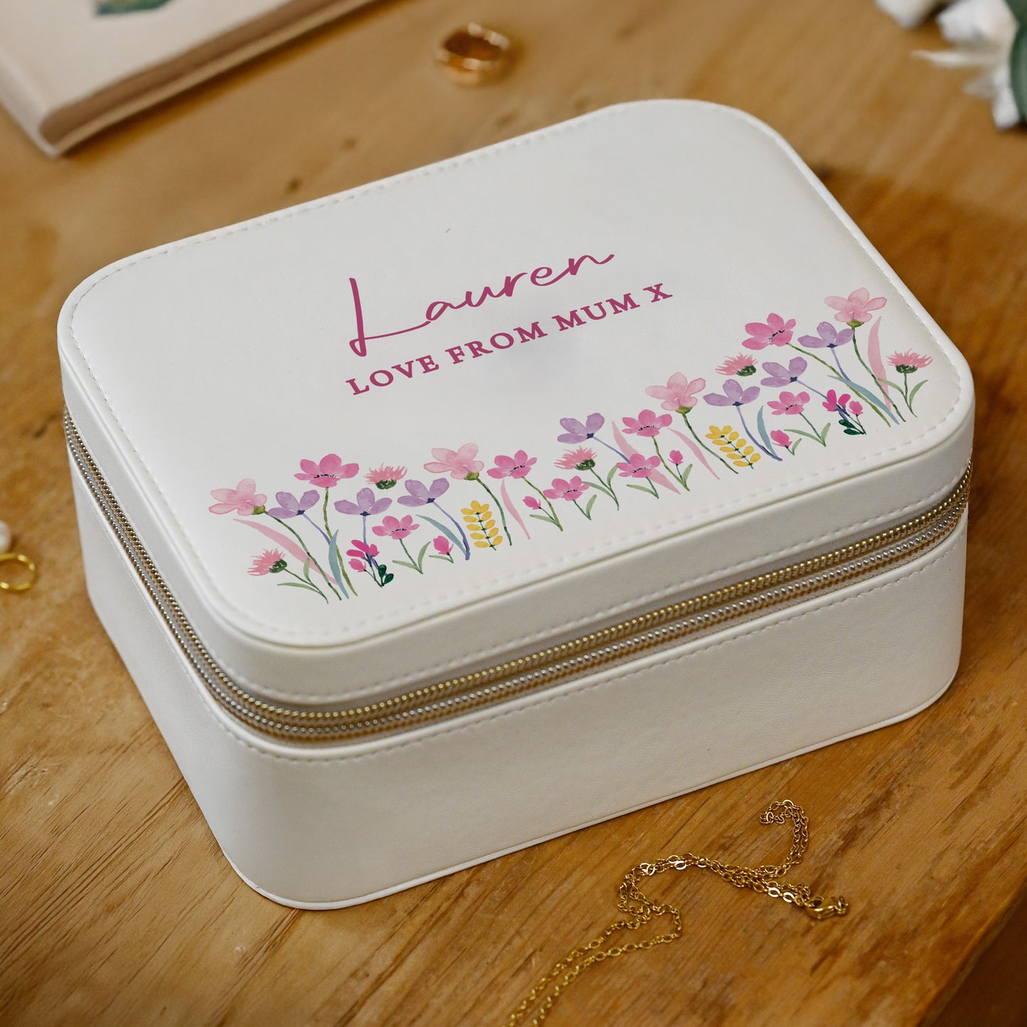 White jewelry box with floral design and embroidered text on a wooden surface