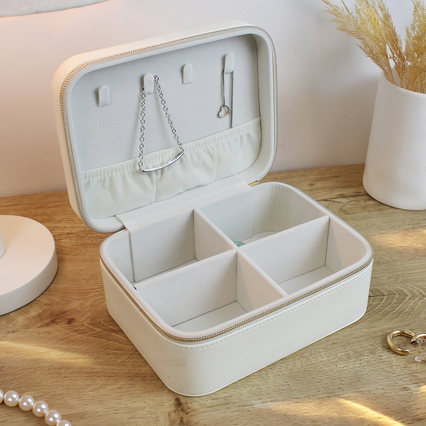 Beige jewelry box with compartments on a wooden surface