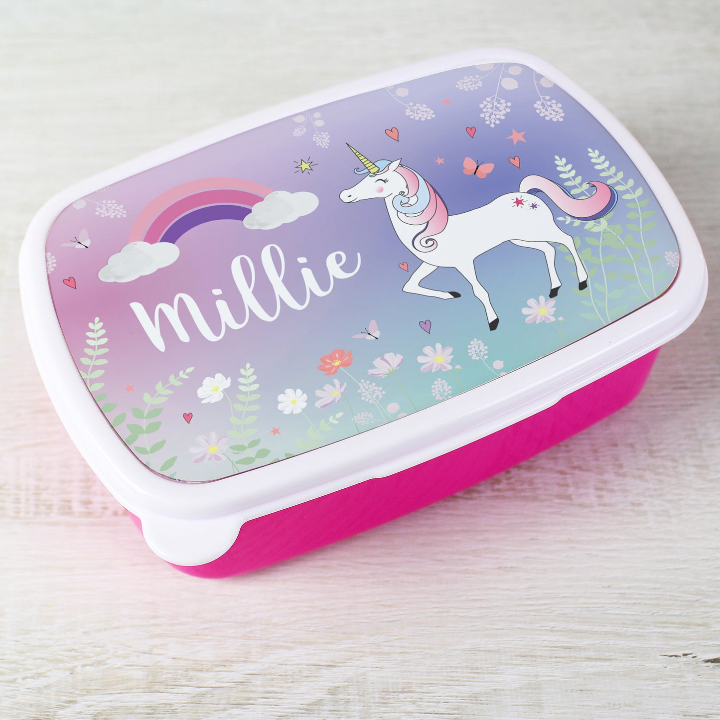 Lunch box with unicorn design and 'Millie' text on a light wooden surface