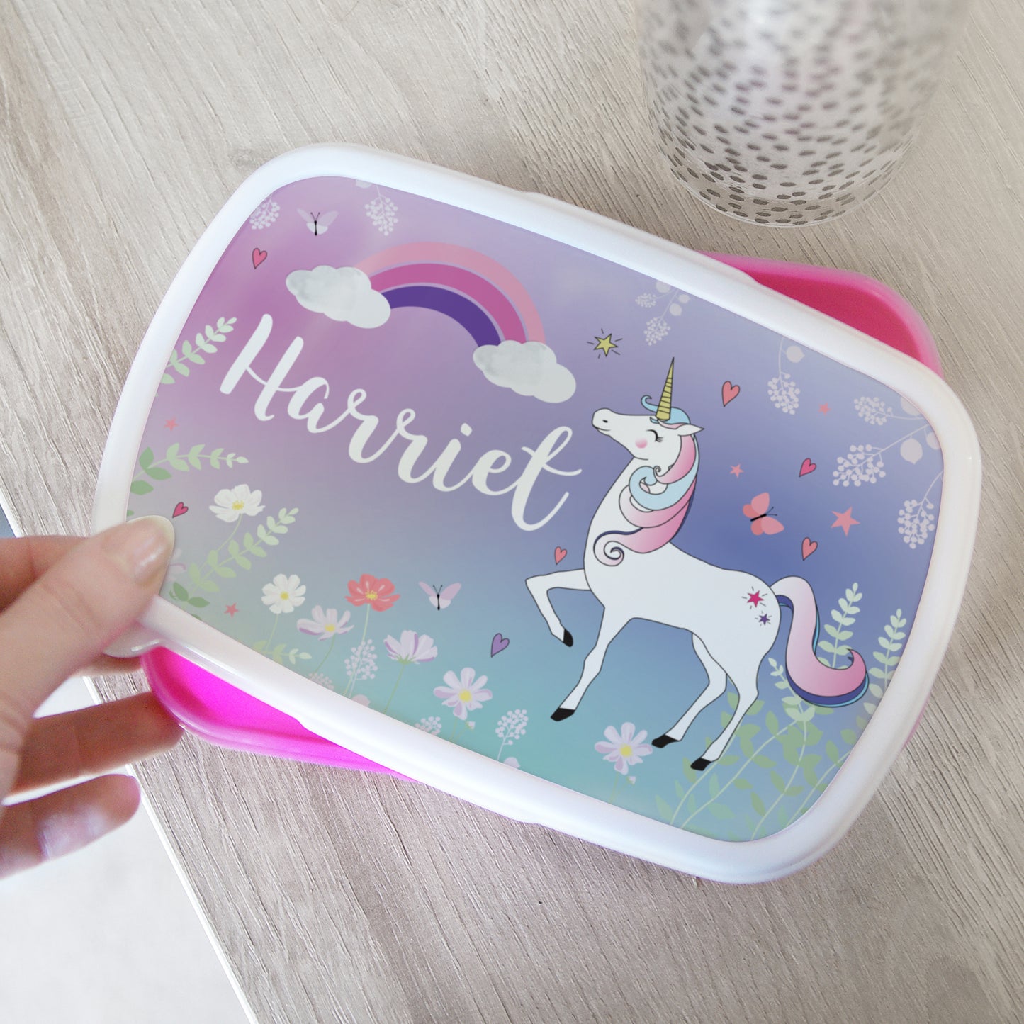 Personalised lunch box with unicorn design and name 'Harriet' on a wooden surface