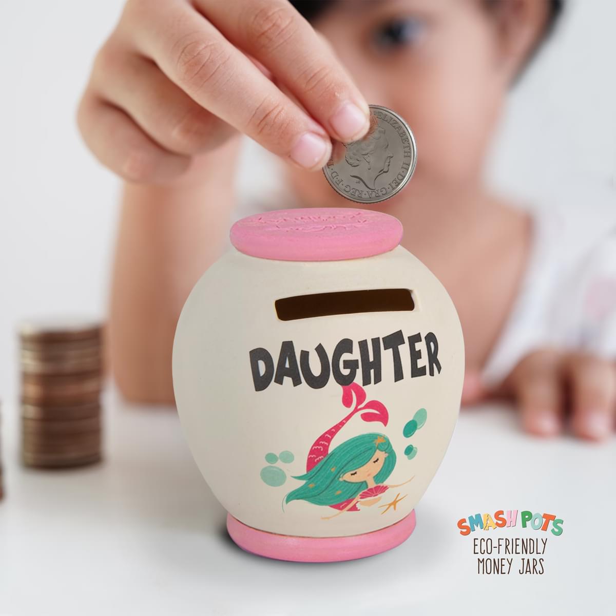 Daughter single use Smash pot money box. In ivory with pink top and base. Colourful mermaid image. Once full, smash and then bury in the compost heap!