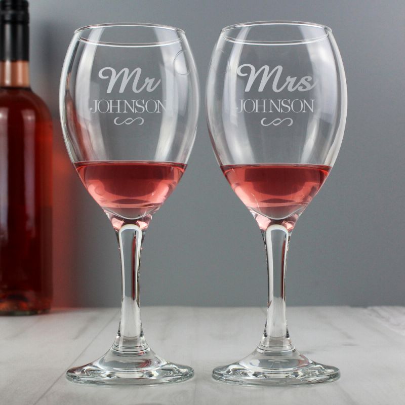 Two wine glasses with 'Mr Johnson' and 'Mrs Johnson' engraving, filled with red wine, on a grey background.