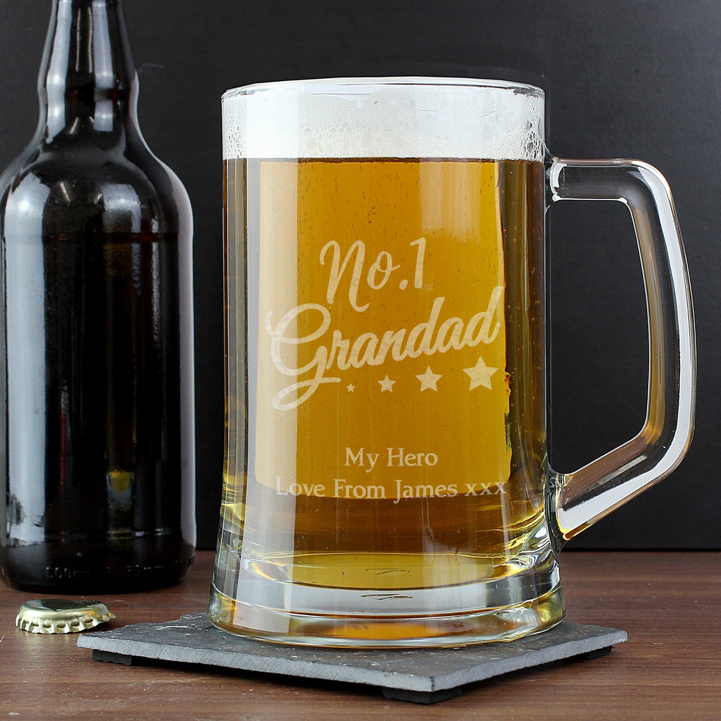 Glass mug with 'No.1 Daddy' engraving next to a bottle on a dark background