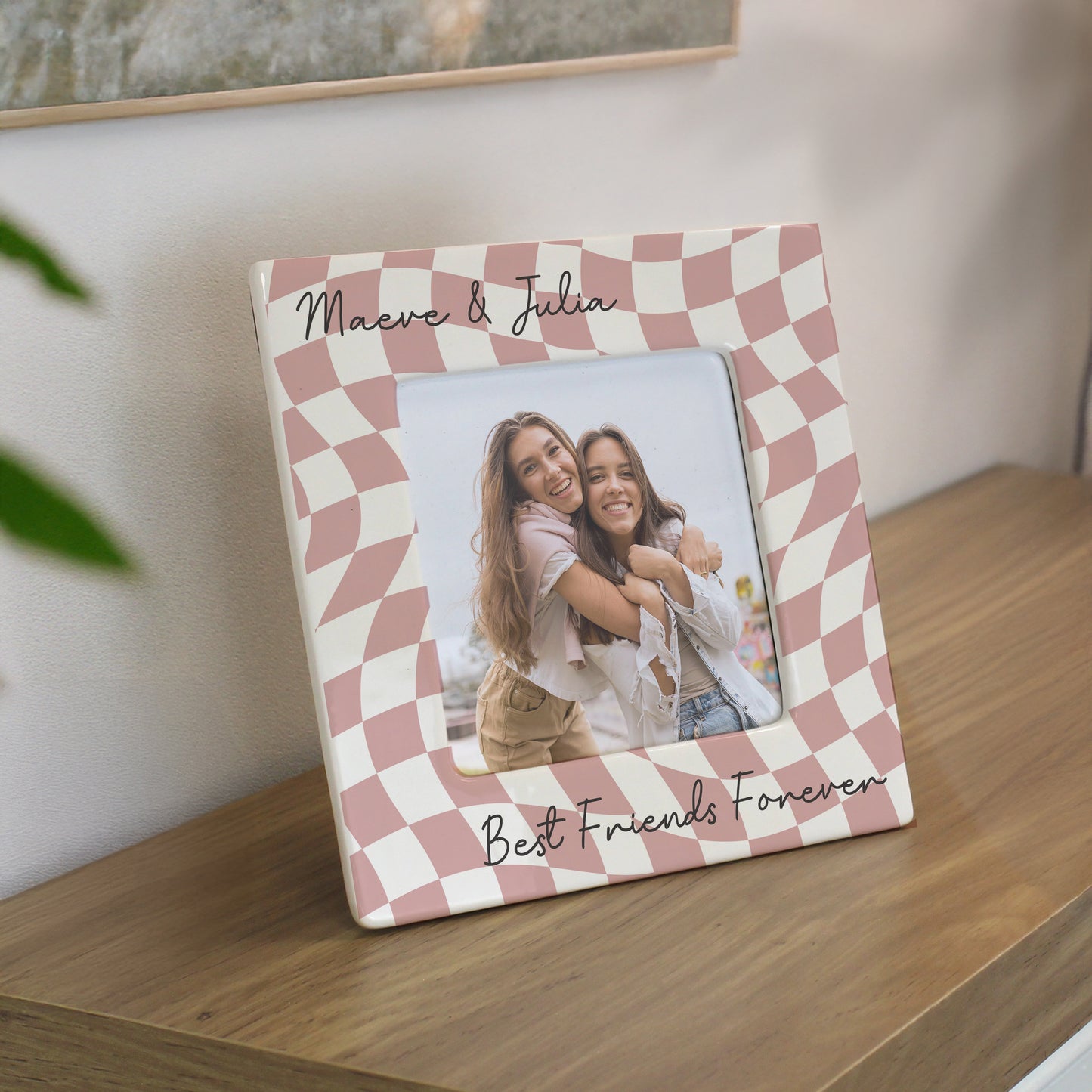 Checkered photo frame with a photo of two people and 'Best Friends Forever' text on a wooden surface.