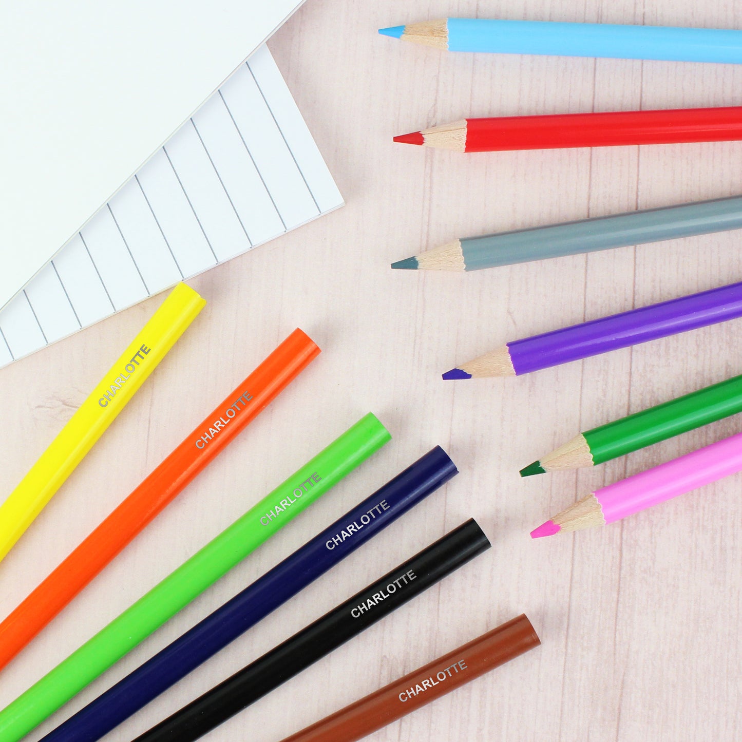 Colorful pencils with 'Charlotte' branding on a wooden surface