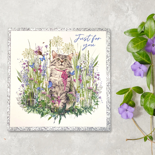 Front image showing a cat with pink ribbons among wild flowers, with silver glitter border