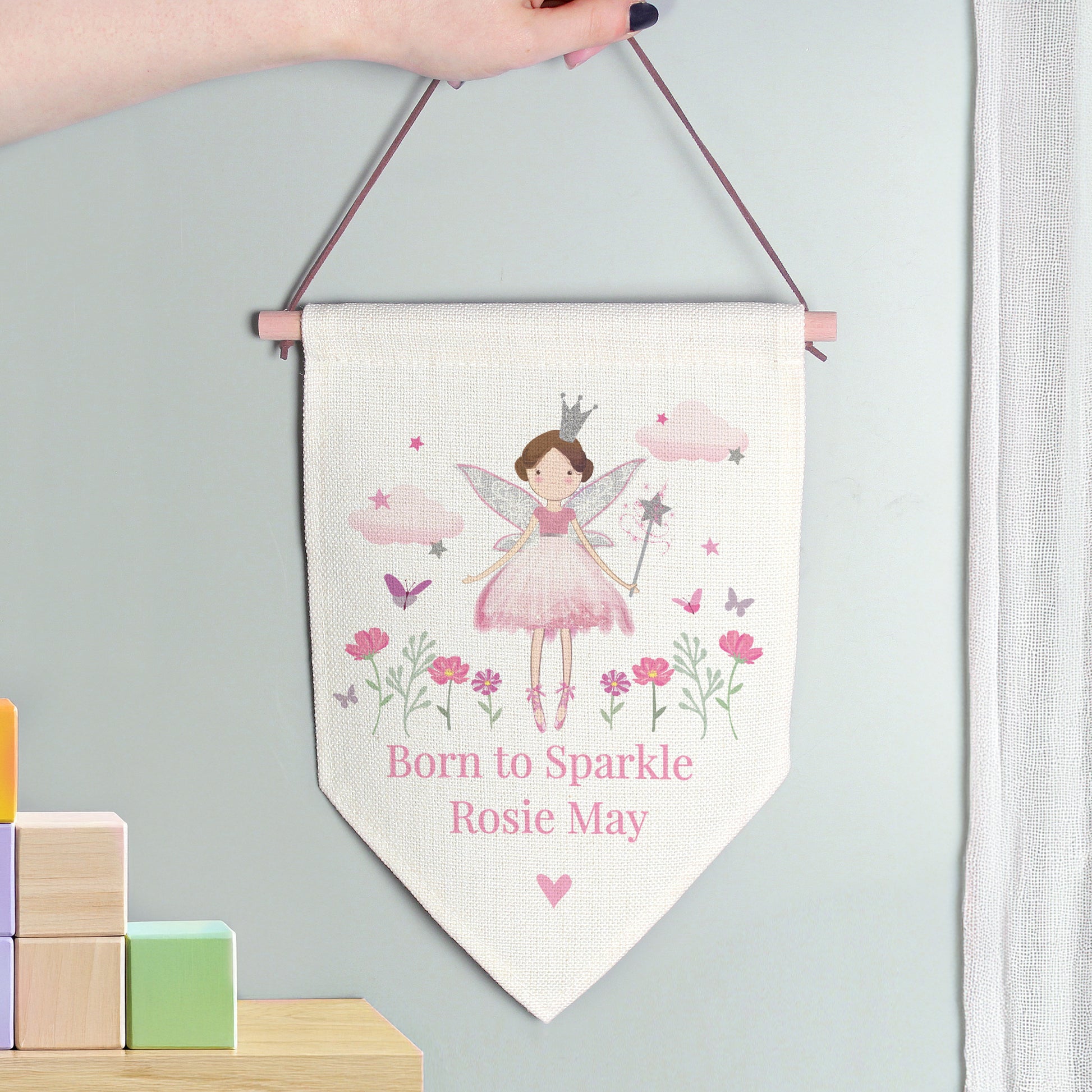 Fairy-themed banner with text hanging on a light gray wall with colorful blocks below.