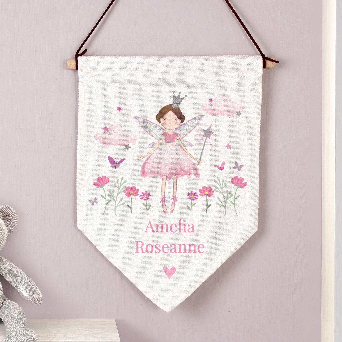 Fairy-themed decorative banner with flowers and a name on a light purple wall.
