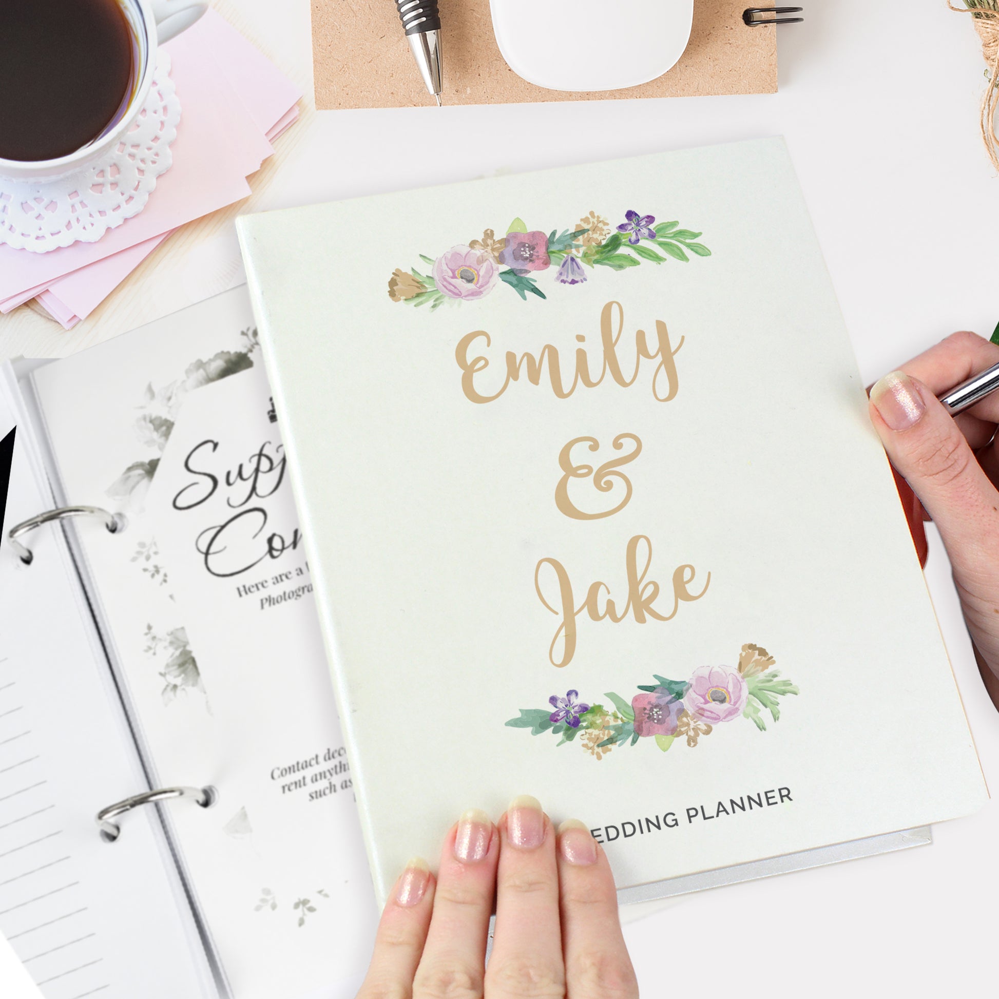 Wedding planner book with floral design and 'Emily & Jake' text, held by a hand.