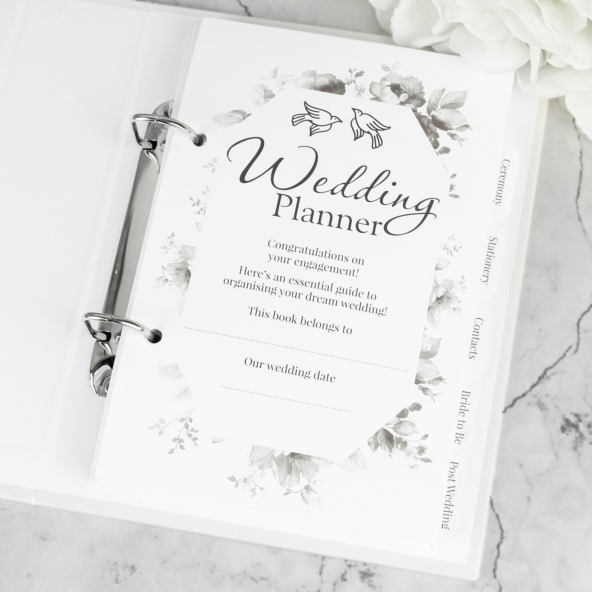 Wedding planner book on a marble surface with floral design