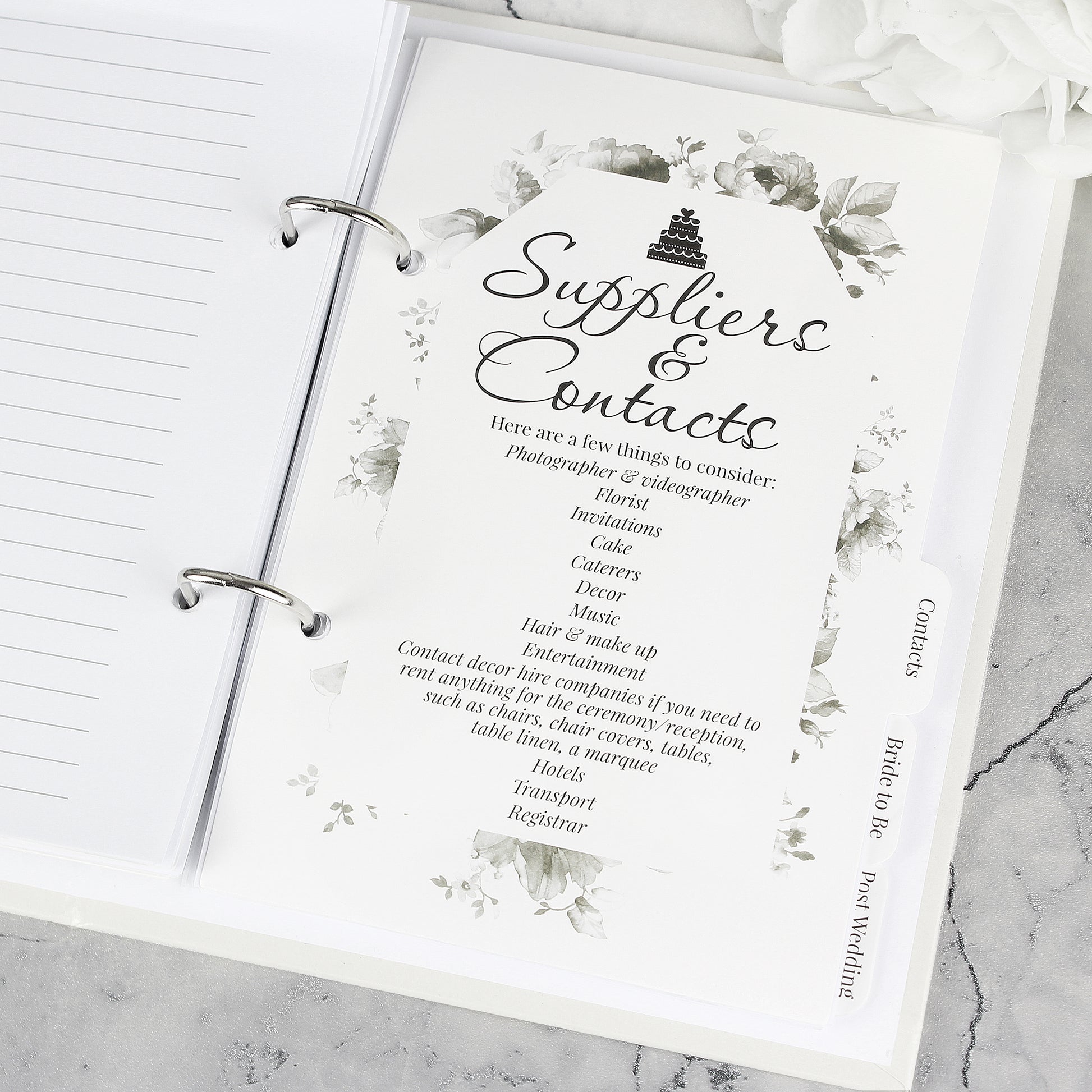 Wedding planning binder with 'Suppliers & Contacts' page on a marble surface