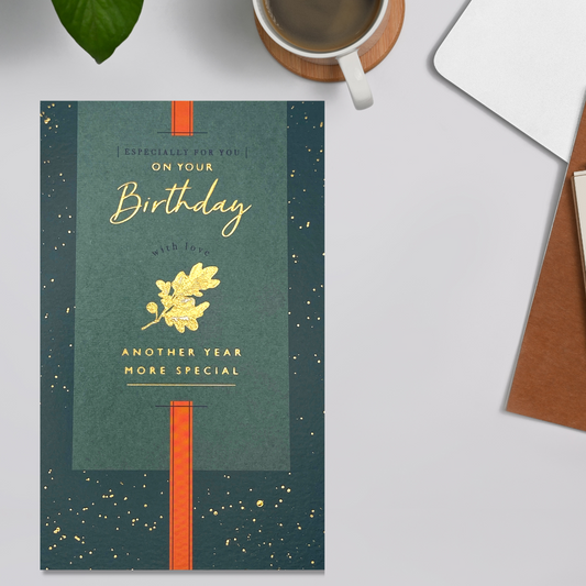Green card with gold foil leaf design, text and accents with bold orange stripe