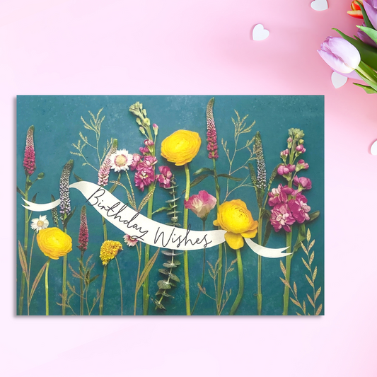 Turquoise background with pink and yellow flowers laid flatlay on top