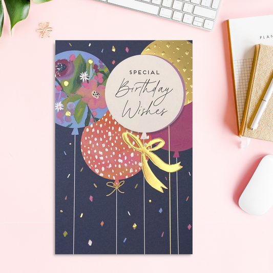 Bold navy card with pretty coloured balloons with gold foil details and embossed finishes