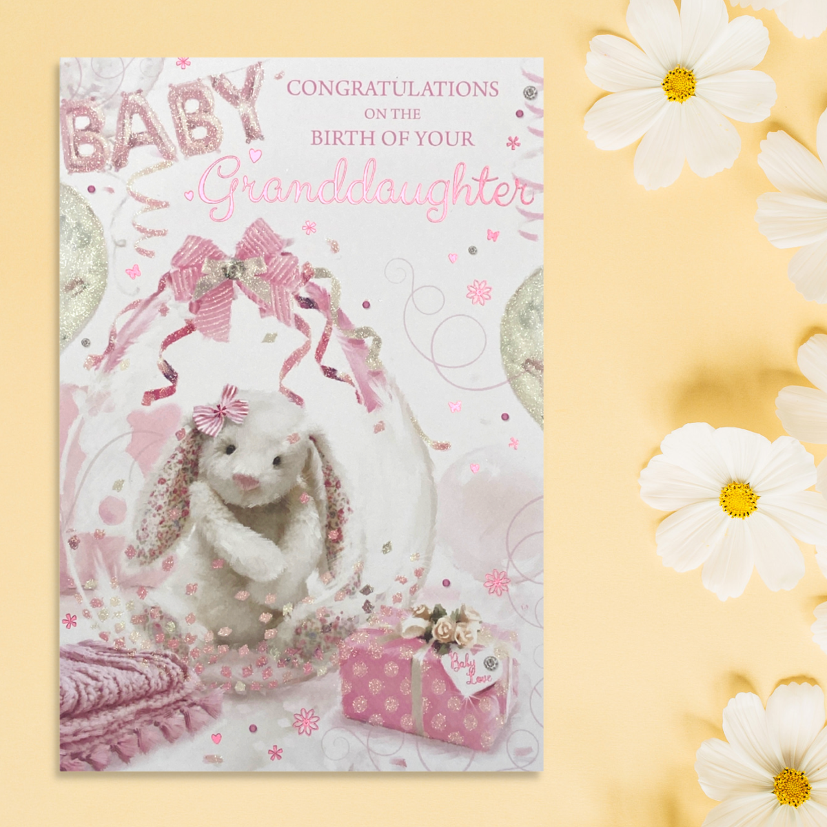 Front image of Granddaughter Birth card with cute white bunny in decorated balloon, with gifts and decorations
