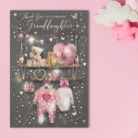 Grey card with selection of pink toys, teddies and clothes on shelves with gold foil accents