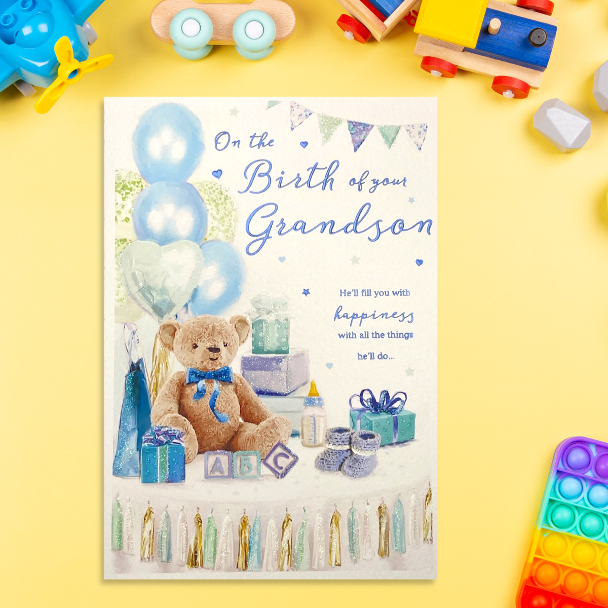 Front image with teddy bear, surrounded by blue gifts and balloons